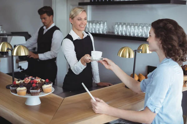 Kellnerin bietet Kunden Tasse Kaffee an — Stockfoto