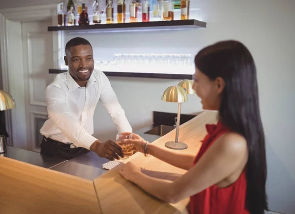 Waiter serving glass of whisky to woman — Stock Photo, Image