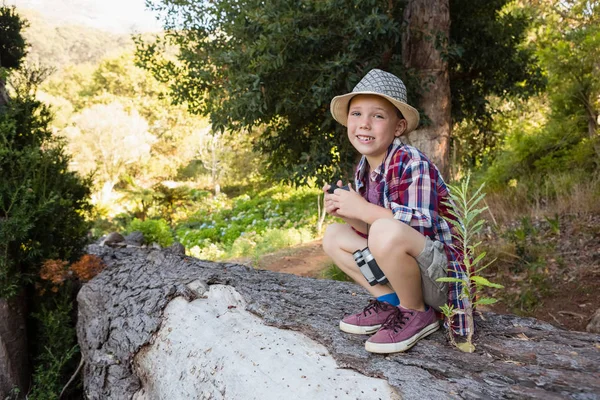 Chlapce, který seděl na kmen stromu v lese — Stock fotografie