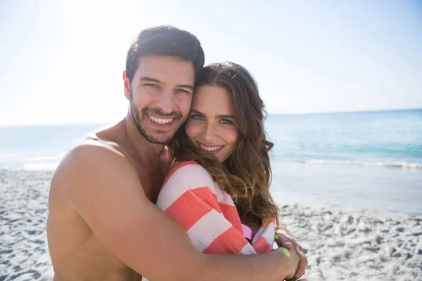 Sorridente giovane coppia che abbraccia in spiaggia — Foto Stock