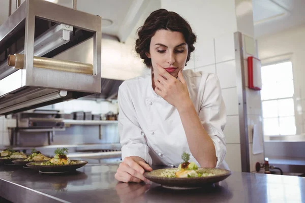 Жіночий шеф-кухар вивчає закуску тарілки — стокове фото