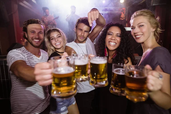 Amigos segurando canecas de cerveja na boate — Fotografia de Stock