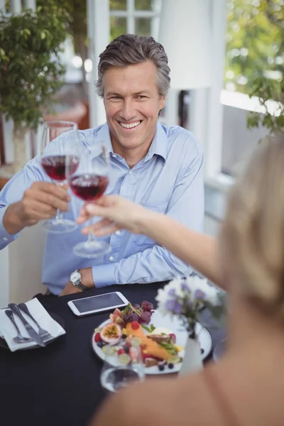 Paar stößt beim Essen auf Weinglas an — Stockfoto