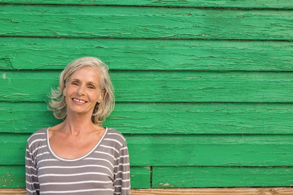 Donna anziana in piedi contro muro verde — Foto Stock