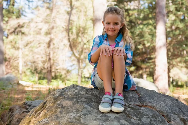 Lachende meisje zittend op de rots in het bos — Stockfoto