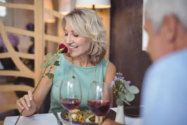 Femme mûre sentant une fleur rose — Photo