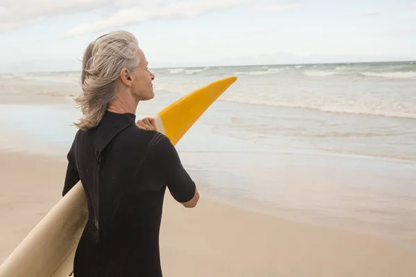 Vrouw met surfplank terwijl staande op de oever — Stockfoto