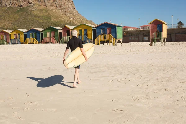 砂の上を歩いてサーフボードを持つ男 — ストック写真