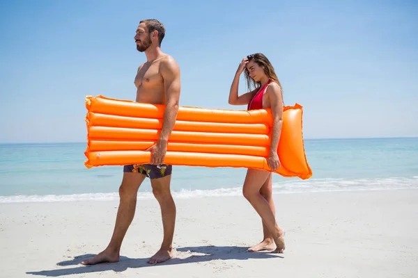 Side view of couple carrying pool raft — Stock Photo, Image