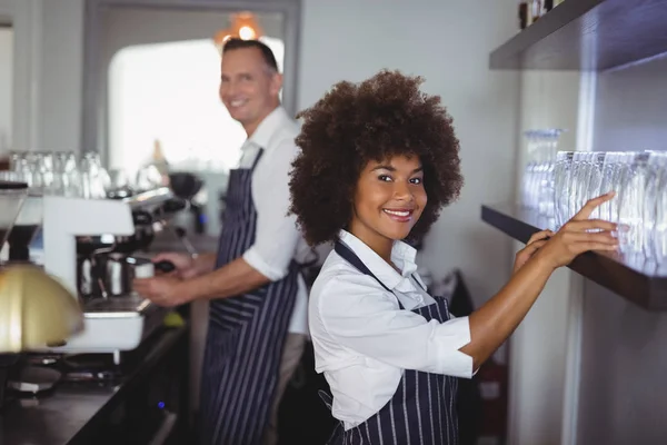 Serveuse arrangeant le verre dans l'étagère au comptoir — Photo