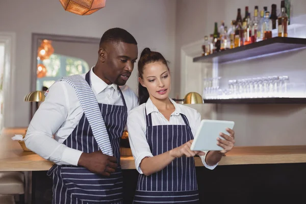 Waiter and waitress discussing over tablet — Stock Photo, Image
