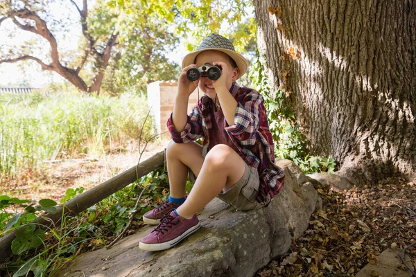 Boy looking through binoculars in forest — Stock Photo, Image