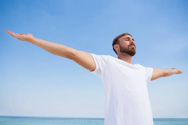 Man med armarna utsträckta tränar på stranden — Stockfoto