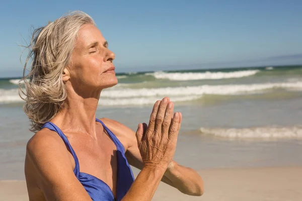 Seniorin meditiert am Strand — Stockfoto