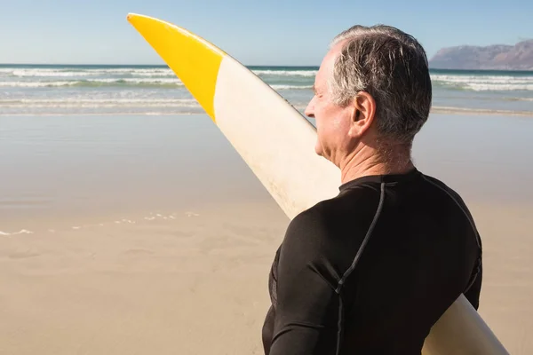 Uomo anziano che trasporta tavola da surf — Foto Stock