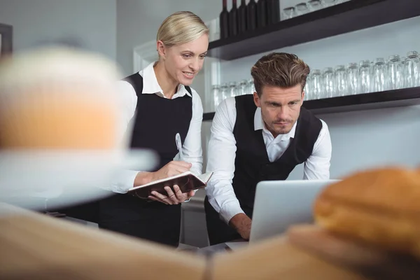 Waiters using laptop at counter — Stock Photo, Image