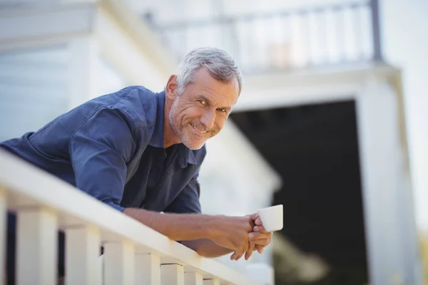 Muž, který držel šálek kávy v balkon — Stock fotografie