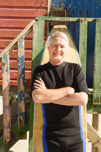 Homme âgé souriant debout près de la planche de surf — Photo