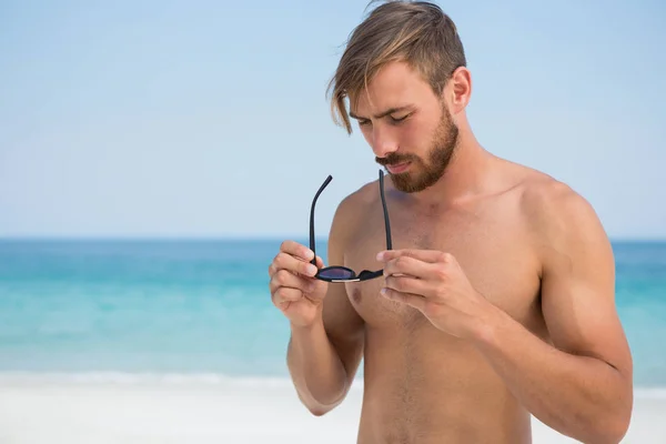 Hombre sin camisa sosteniendo gafas de sol — Foto de Stock