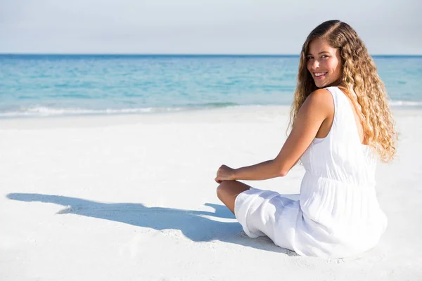 Улыбающаяся женщина сидит на пляже — стоковое фото