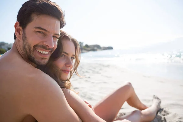 Uomo senza maglietta con la sua ragazza seduta in spiaggia — Foto Stock