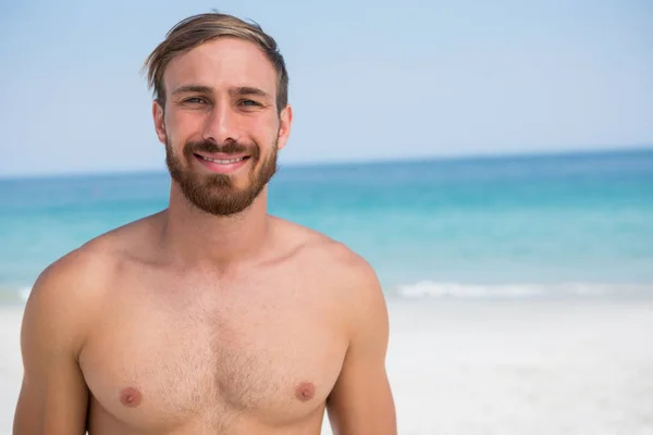 Hombre sin camisa de pie en la playa — Foto de Stock