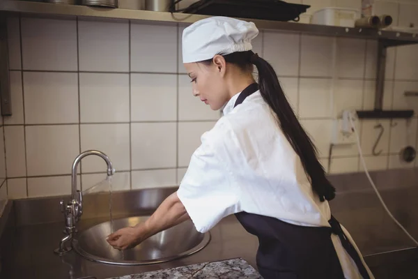 Vrouwelijke chef-kok handenwassen in keuken — Stockfoto