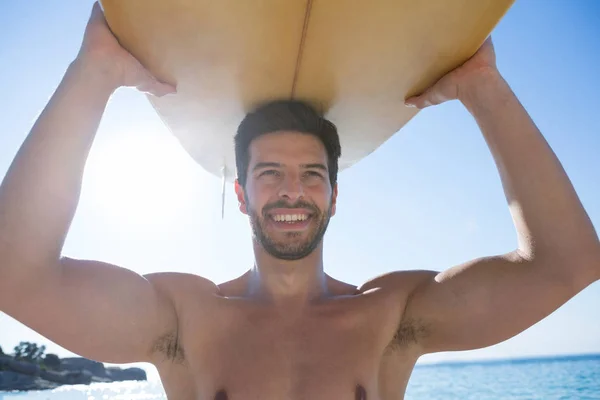 Hombre sin camisa llevando tabla de surf en la playa — Foto de Stock