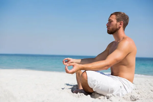 Homme torse nu méditant à la plage — Photo