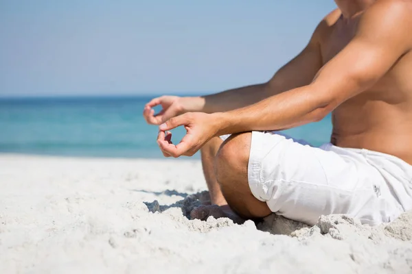 Shirtless man mediteren op strand — Stockfoto