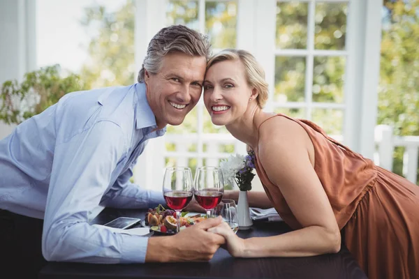 Couple holding hands while having meal — Stock Photo, Image