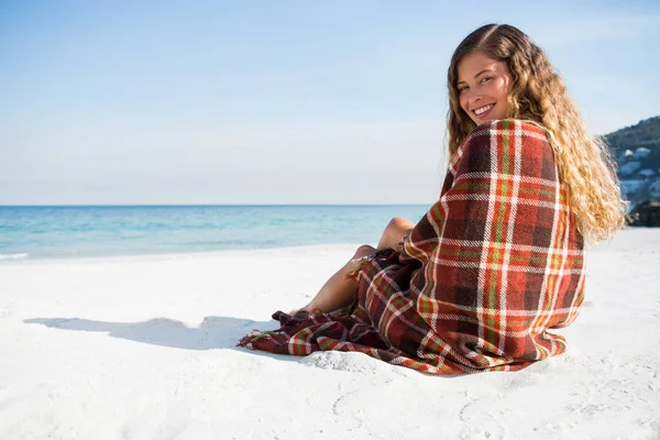 Leende kvinna som sitter på stranden — Stockfoto