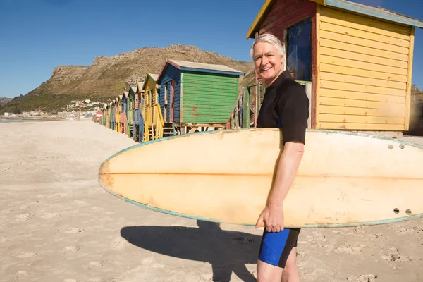 Homme souriant portant planche de surf — Photo