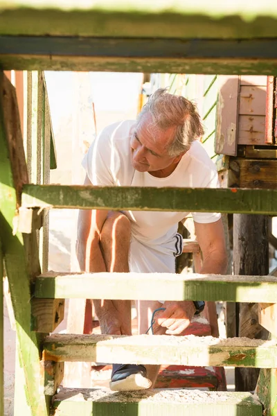 Uomo anziano allacciatura lacci delle scarpe mentre sui gradini — Foto Stock