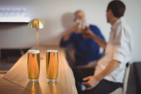 Vasos de cerveza en mostrador con los clientes —  Fotos de Stock