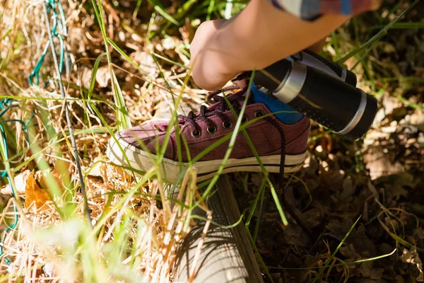 Boy tying shoelace in the forest — Stock Photo, Image