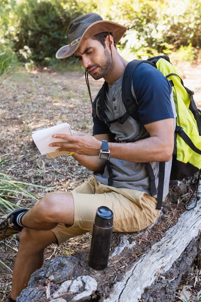 Homme écrivant sur le bloc-notes tout en se reposant — Photo