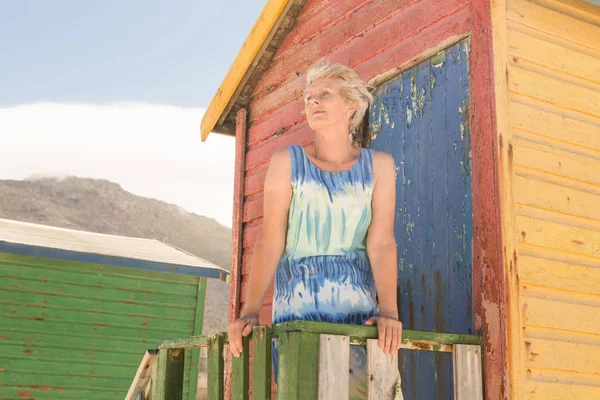 Mujer mirando hacia la cabaña de la playa — Foto de Stock