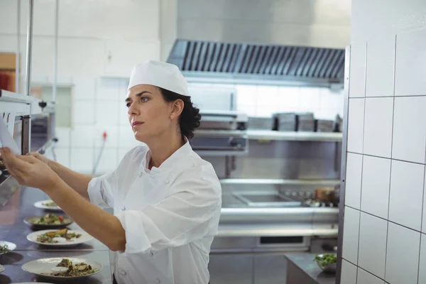 Vrouwelijke chef-kok een bestellijst kijken — Stockfoto