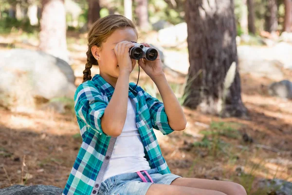 Flickan tittar genom kikaren i skogen — Stockfoto