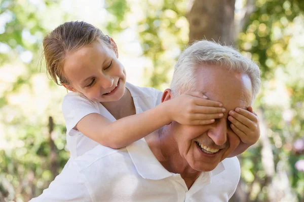 Chica cubriendo los ojos de su abuelo — Foto de Stock
