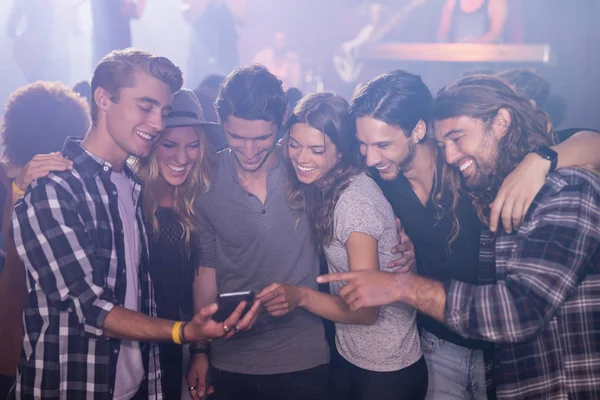 Amigos mirando el teléfono inteligente en discoteca — Foto de Stock