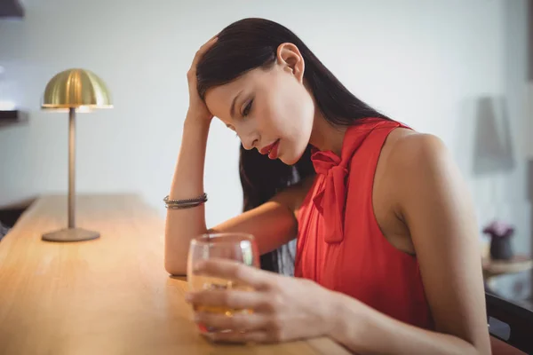 Mujer pensativa tomando un vaso de whisky —  Fotos de Stock