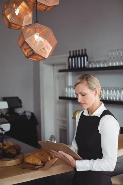 Servitrisen skriver om anteckningar på counter — Stockfoto