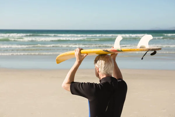 Senior mand holder surfbræt - Stock-foto