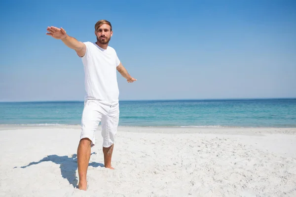 Man practicing warrior 2 pose at beach — Stock Photo, Image