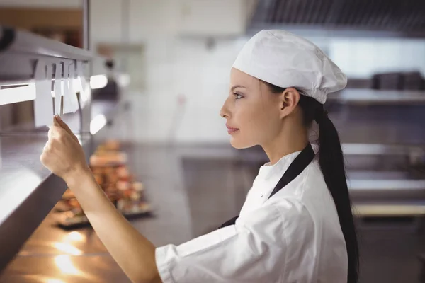 Chef donna guardando una lista degli ordini in cucina — Foto Stock