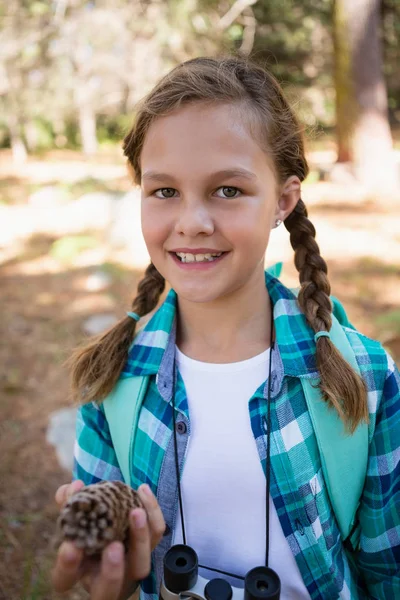 Girl looking at pine cone in forest — Stock Photo, Image