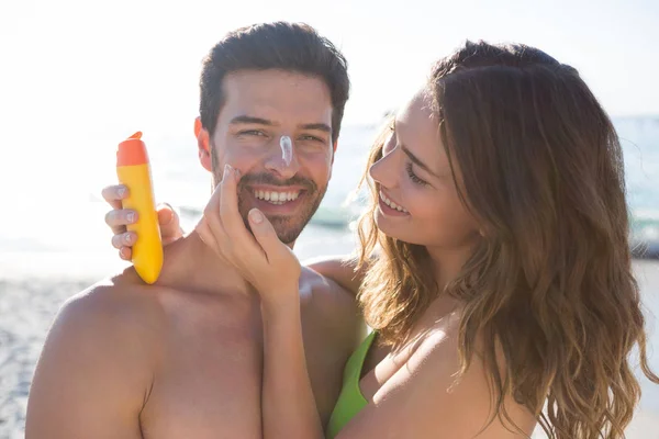 Kvinna applicera solskydd på leende ansikte människan — Stockfoto