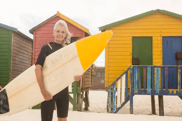 女人携带冲浪板对小屋 — 图库照片